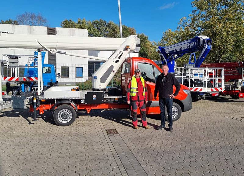 Zwei Mitarbeiter stehen vor einer Hebebühne